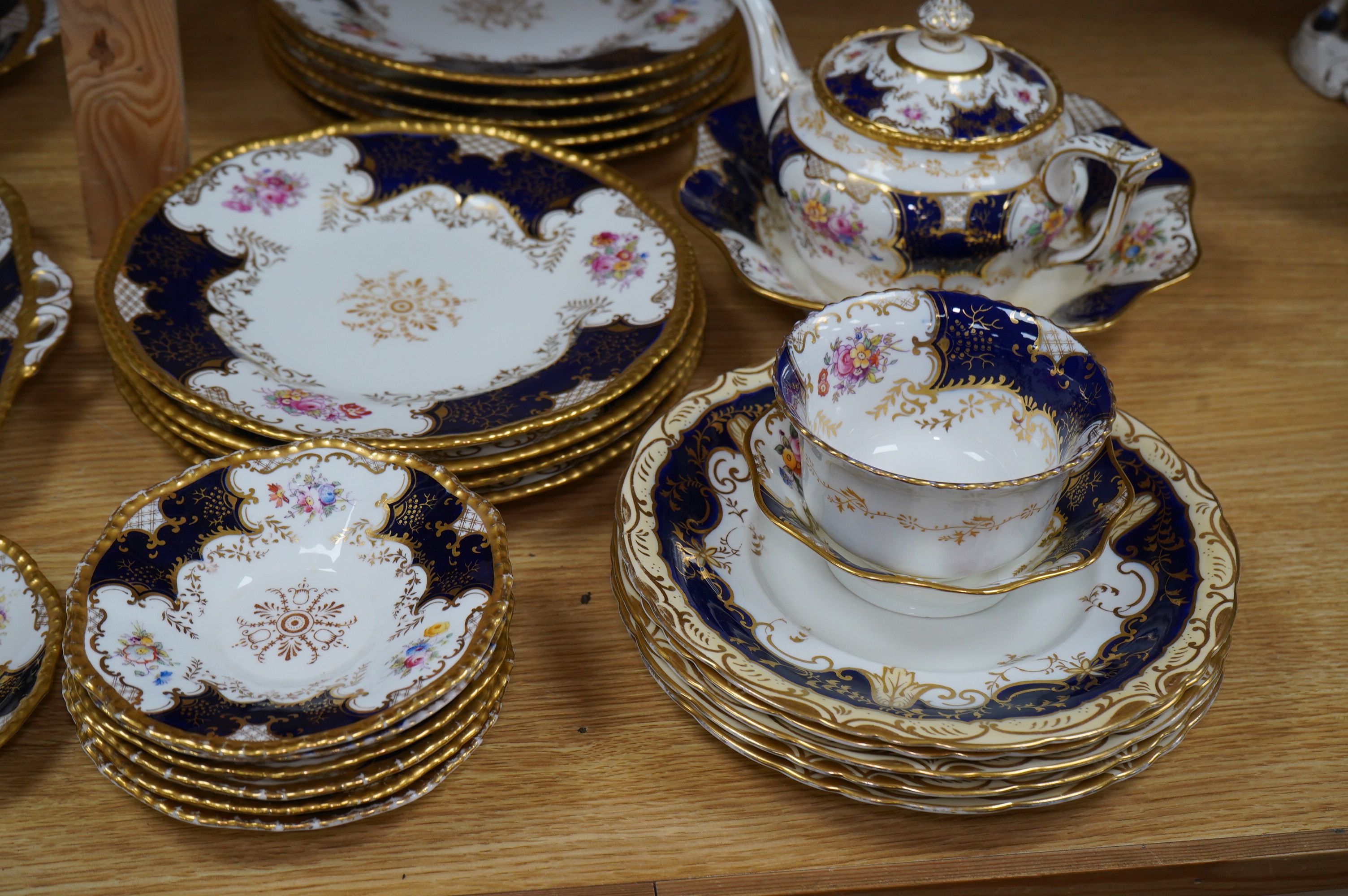 A late 19th/early 20th century Coalport blue and gilt bordered floral painted part tea and dessert service, largest 32cm wide. Condition - varies